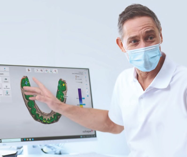 Ein Arzt zeigt auf einen Bildschirm mit einem digitalen Zahnmodell.