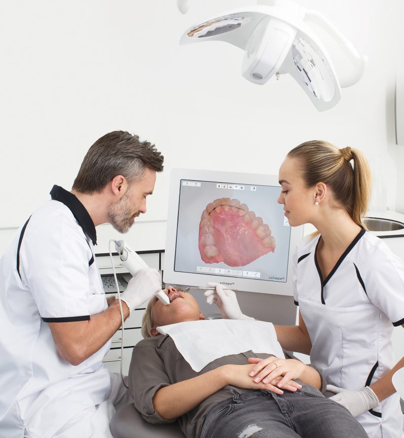 Zahnärztliches Team untersucht einen Patienten am Behandlungsstuhl.