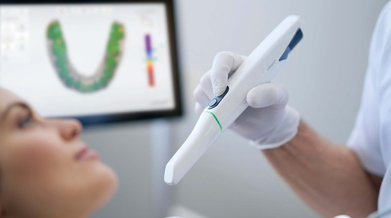 Zahnärztliche Untersuchung mit einem digitalen Scanner und einer Patientin.